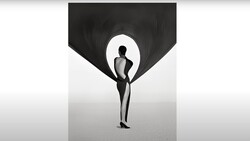 Silhouetted figure holding billowing black fabric against a bright backdrop.