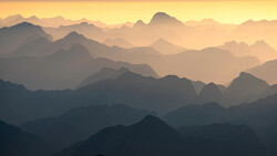 Layered mountain silhouettes fading into atmospheric haze at sunrise or sunset.