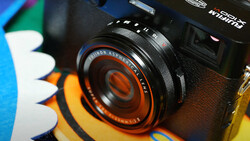 Vintage Minolta camera lens with orange and black detailing mounted on camera body.