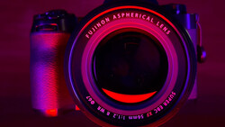 Vintage camera with neon pink and blue lighting against dark purple background.