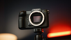 Fujifilm medium format camera body mounted on tripod with warm and cool studio lighting in background.