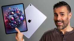 Man holding iPad displaying vibrant digital artwork of colorful mechanical gears and spheres.