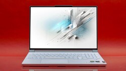 Silver laptop displaying abstract geometric 3D design with blue light streaks on red background.
