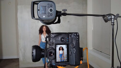 Behind-the-scenes view of a portrait photography setup with a large-format camera displaying a live image of a woman on its LCD screen.