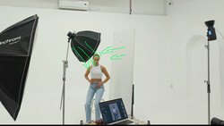 Studio portrait setup with model posing under softbox lighting and green neon sign graphic.