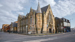 Stone Victorian-era church with Gothic spires at a street corner intersection.