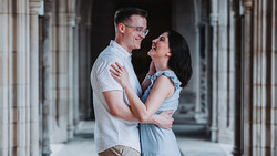 Couple smiling at each other in a columned hallway with soft natural light.
