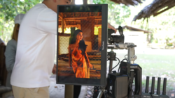 Cinematographer monitoring footage on external monitor during outdoor film production.