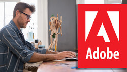 Designer working at desk with wooden mannequin and Adobe logo displayed.