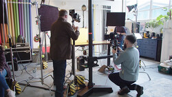 Professional photography studio setup with crew operating camera equipment and lighting rigs during a production shoot.