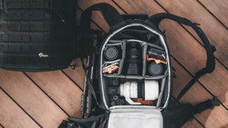 Camera backpack interior with organized gear compartments showing lenses, camera body, and accessories.