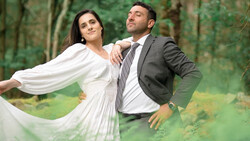 Bride and groom posing together in a forest setting with flowing white fabric.