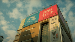 Modern building with red and yellow roofline signage against blue sky with white clouds.