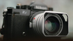 Leica rangefinder camera with silver lens in sharp focus, black film camera body blurred in background.