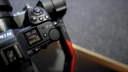 Close-up of a mirrorless camera's control dial and rear LCD screen showing exposure settings.