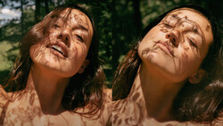 Two women with long dark hair looking upward, dappled sunlight creating shadow patterns across their faces.