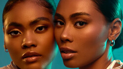 Two women with warm-toned skin positioned close together against a turquoise background.