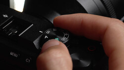 Photographer's hand adjusting the mode dial on a professional camera body.