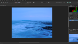 Coastal seascape at dusk with rocky shoreline and calm blue water under twilight sky.