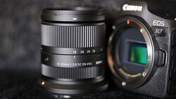 Canon EOS R7 camera body with Canon RF 18-50mm f/2.8 DC DN Contemporary lens on dark surface.