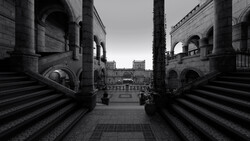 Symmetrical view down a columned corridor toward a distant piazza with classical architecture.