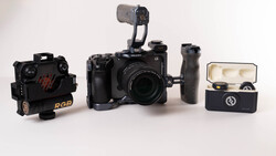 Video production kit with cinema camera, RGB light, wireless microphone, and accessories on white surface.