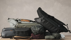 Collection of camera bags and travel gear organized in a flat lay arrangement against a neutral background.