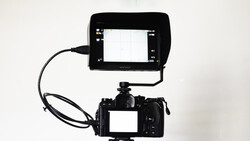 Professional video camera with external monitor mounted on top via cable.