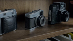 Four vintage rangefinder cameras arranged in a line on a wooden shelf.