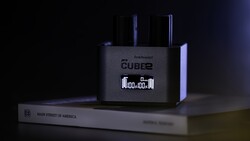 Roland Cube2 amplifier displaying digital clock on dark surface with book beside it.