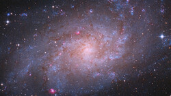 Spiral galaxy with bright central core and blue and pink star-forming regions throughout its disk.