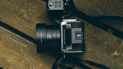 Medium format camera with standard lens and light meter on wooden surface.