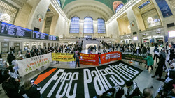 Pro-Palestine demonstration in a grand station with large banners and dozens of participants.