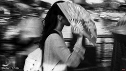 Person in motion holding a fan in front of their face, shot with motion blur and fast shutter speed.