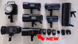 Collection of professional lighting equipment including LED panels, monolights, and wireless triggers arranged on a light surface.
