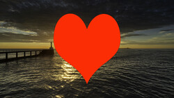 Large red heart shape overlaid on a seascape with a pier and dramatic sunset lighting.