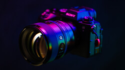 Sony mirrorless camera and lens illuminated with neon magenta and blue lighting against a dark background.
