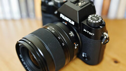 Fujifilm X-T50 mirrorless camera with attached zoom lens on wooden surface.