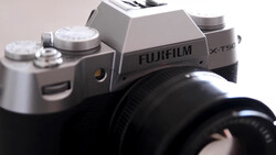 Fujifilm X-T50 mirrorless camera with silver top plate and black lens attached, shot against neutral background.