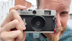 Photographer holding a Canon rangefinder camera with black body and silver top plate.