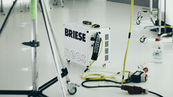 Overhead view of a Briese lighting unit on a white floor with cables and grip equipment arranged around it.