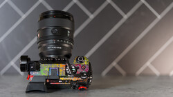 Camera lens mounted on disassembled camera body showing internal circuitry and components.