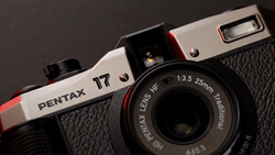 Pentax 17 film camera with red and white body and black leather grip, showing 25mm lens and built-in flash.