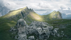 Alpine valley landscape with distinctive layered mountain peaks and weathered limestone rock formations in foreground.