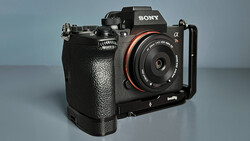 Sony Alpha mirrorless camera with attached L-bracket and prime lens on neutral background.