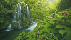 Tiered waterfall cascading through lush green forest with flowering plants in foreground.