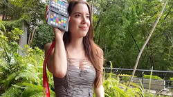 Woman holding a color reference chart outdoors while looking at camera.
