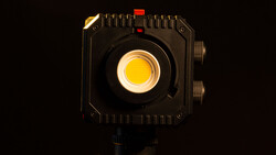 Professional LED light panel with bright yellow center and black housing, lit against dark background.