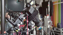 Professional cinema camera rig with follow focus system mounted on support rod in studio setting.