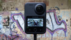 Kandao action camera mounted on stand against colorful graffiti wall backdrop.